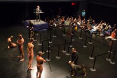 [Clifford Owens, Lawrence Graham-Brown, Wilmer Wilson IV, Rocheford Belizaire, and Dread Scott (on platform) with dog handlers and audience in a scene from the Dread Scott production "Decision" part of "Brooklyn Bred" during the BAM Next Wave Festival, 2012]